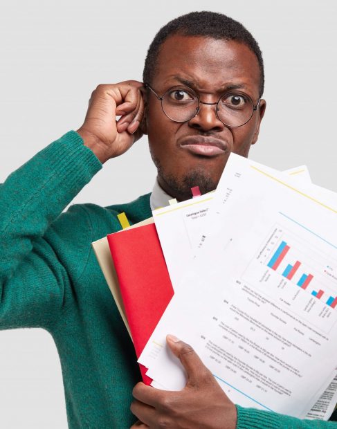 dissatisfied-black-man-prepares-accounting-report-holds-papers-with-inforgraphic-wears-spectacles-good-vision